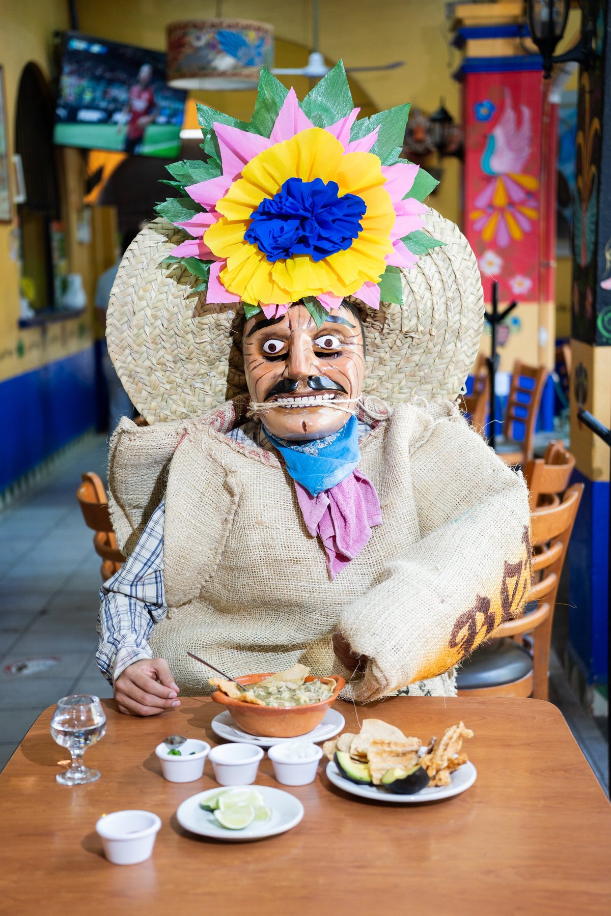 Tlacololero sentado a la mesa con pozole y mezcal de la casa