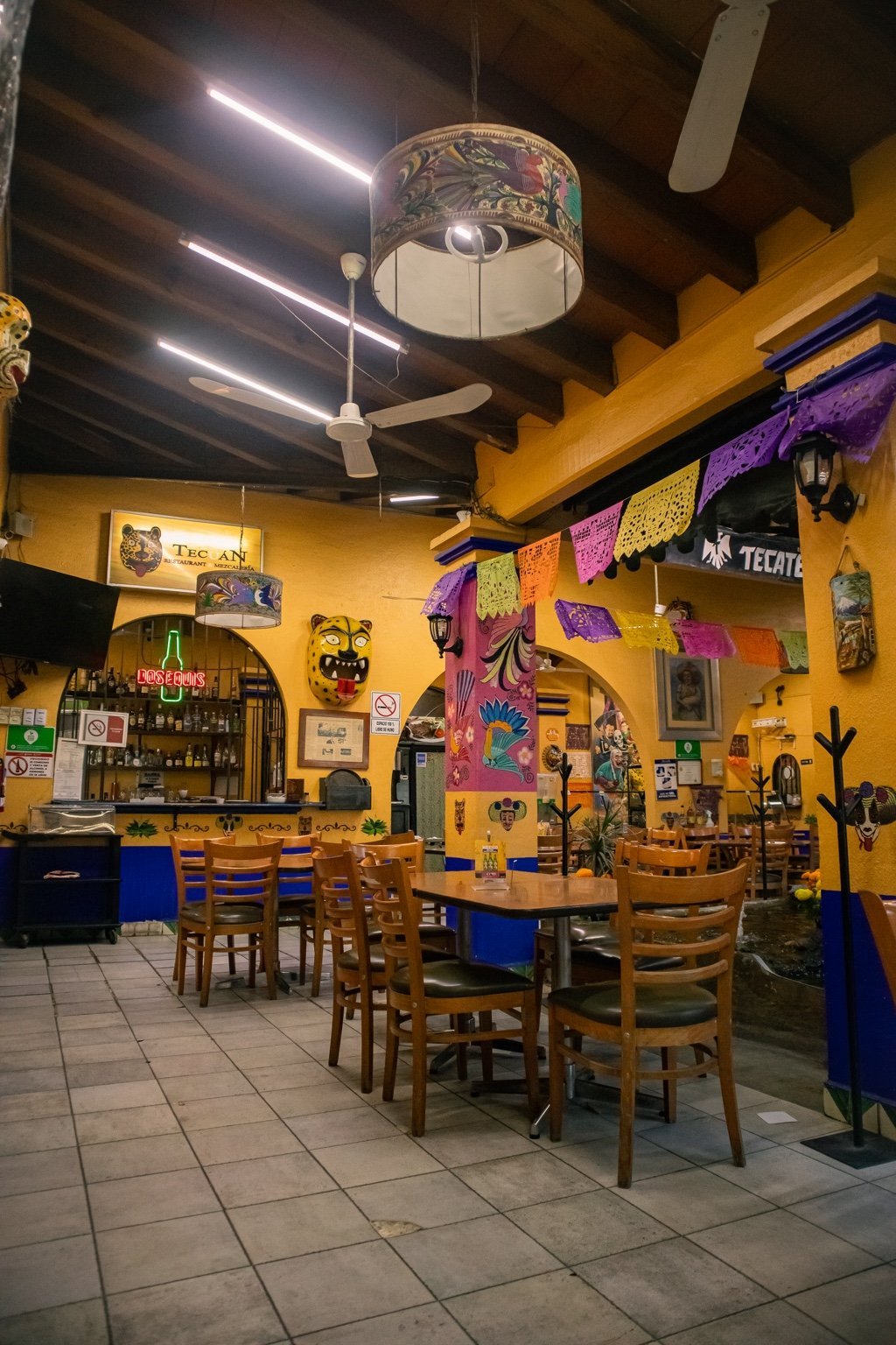 Interior del restaurante Tecuán con paredes amarillas, muebles de madera y barra